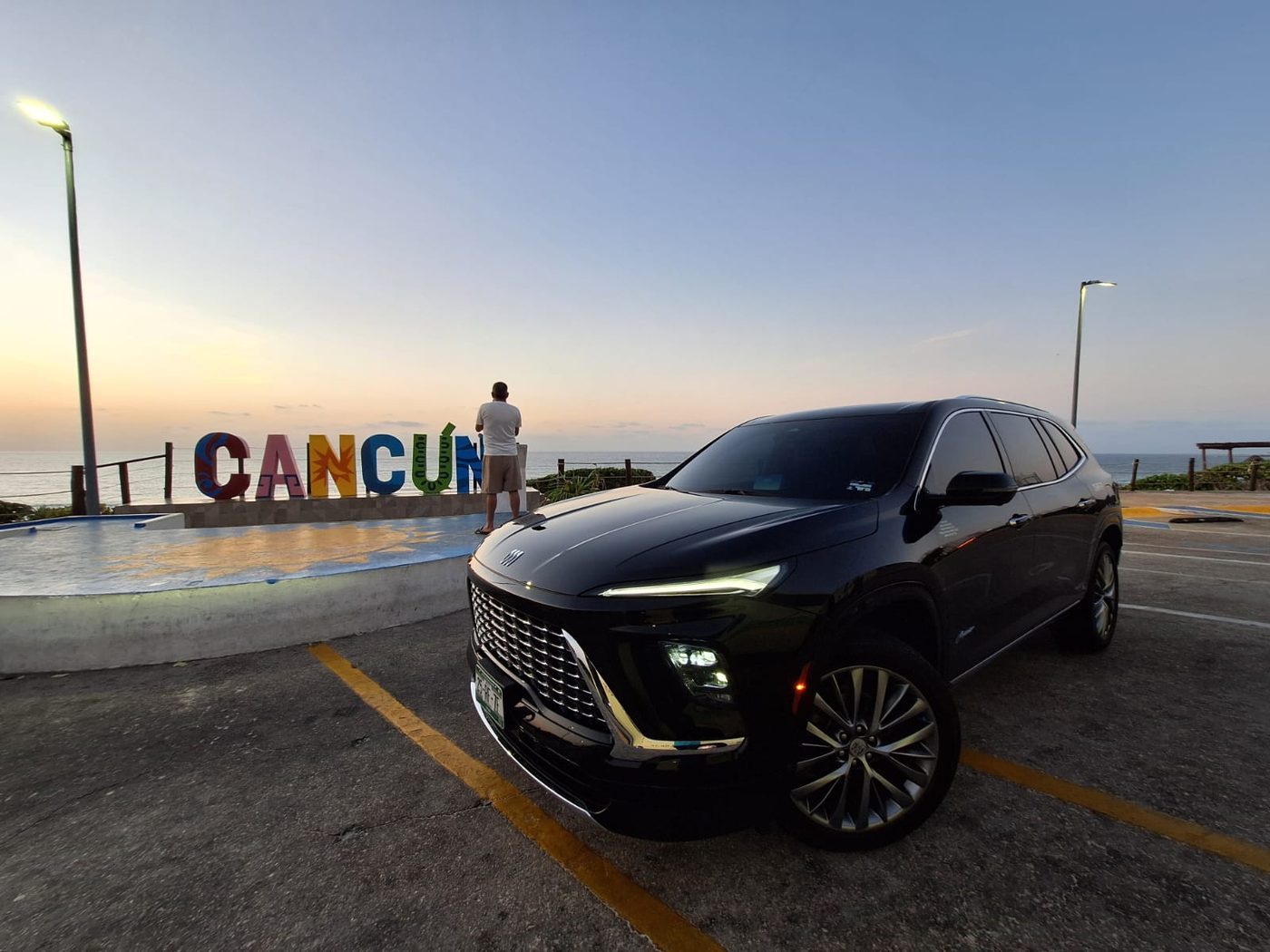 SUV Buick negra de Comfort & Safety Transport frente al letrero de Cancún al atardecer